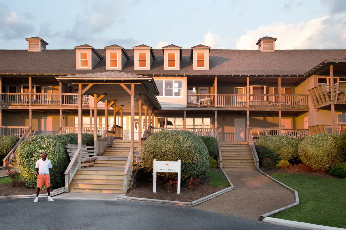 The inviting main entrance of the property, featuring stylish signage, manicured landscaping, and a person pausing on the steps. The scene feels both welcoming and exclusive, setting the tone for a luxurious stay.