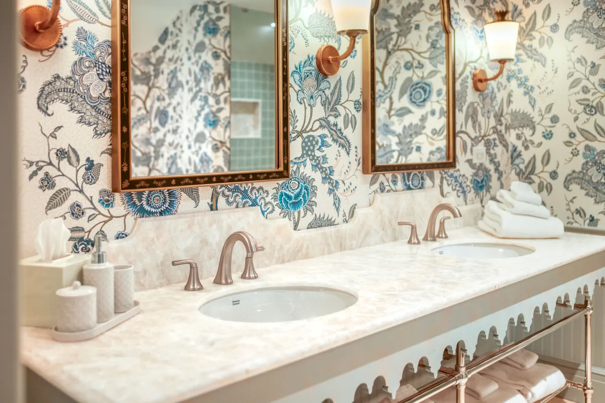 A serene, light-filled bathroom featuring elegant floral wallpaper, a spacious double vanity with gleaming mirrors, and modern light fixtures—crafted for moments of relaxation and self-care.